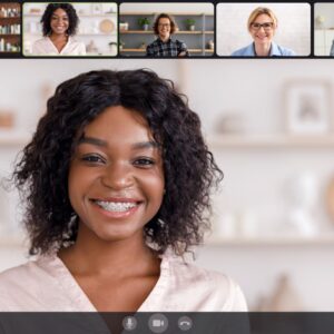 A smiling woman during a video conference call with five other participants.